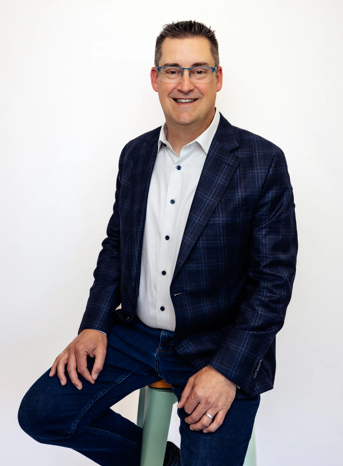 Seated studio portrait in a blue checked suit