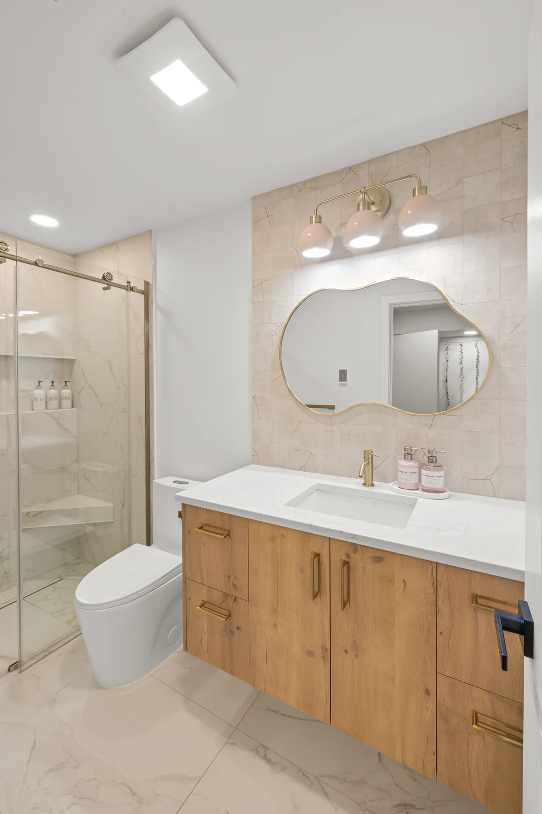 Remodeled bathroom with a wood vanity and round mirror
