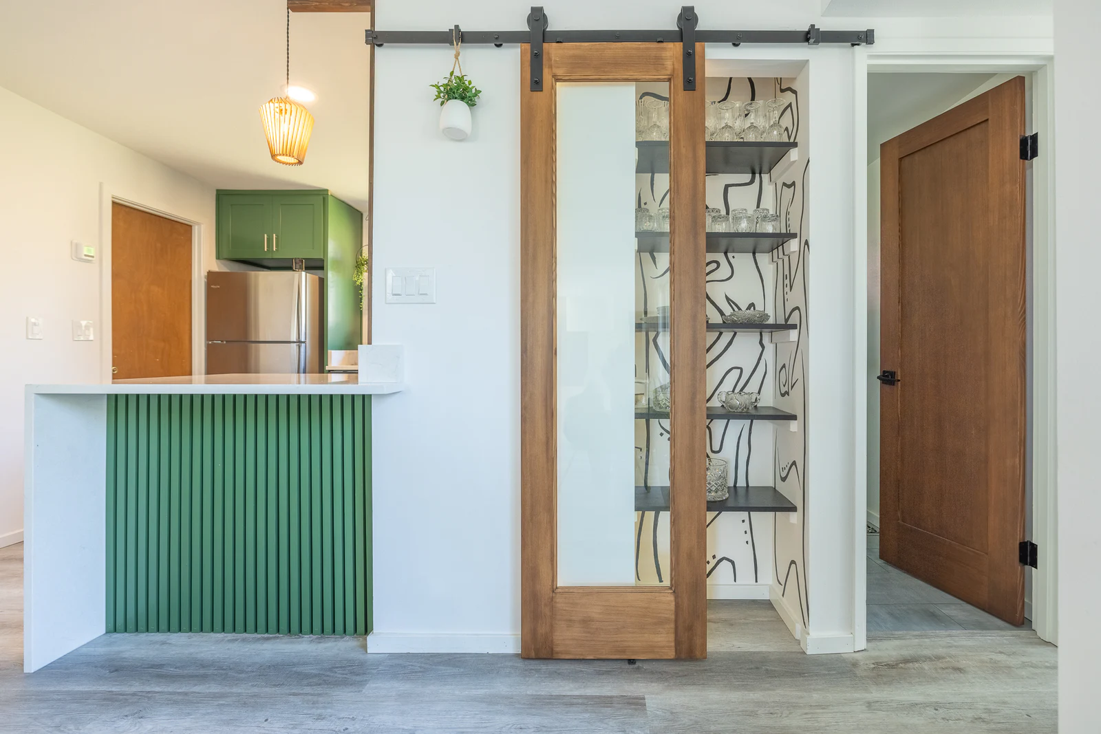 Green home bar beside a sliding wood door