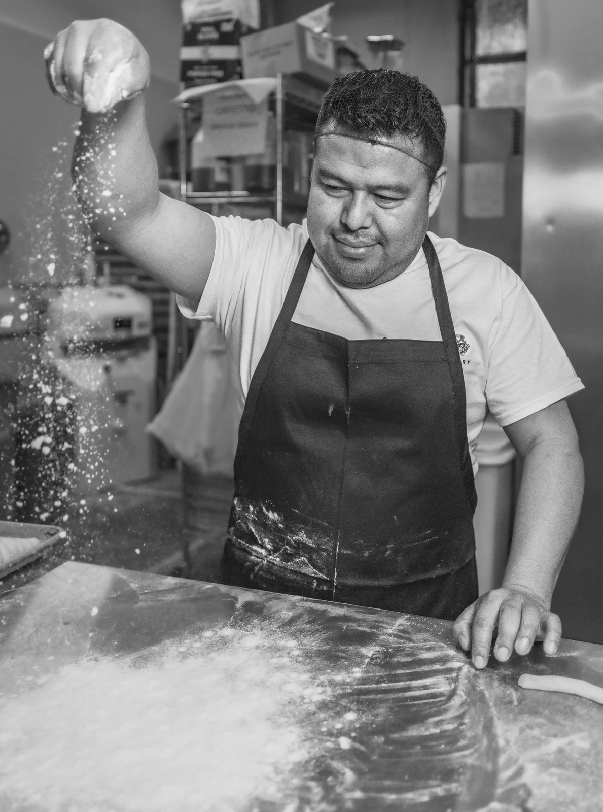 Baker scattering flour across a worktable