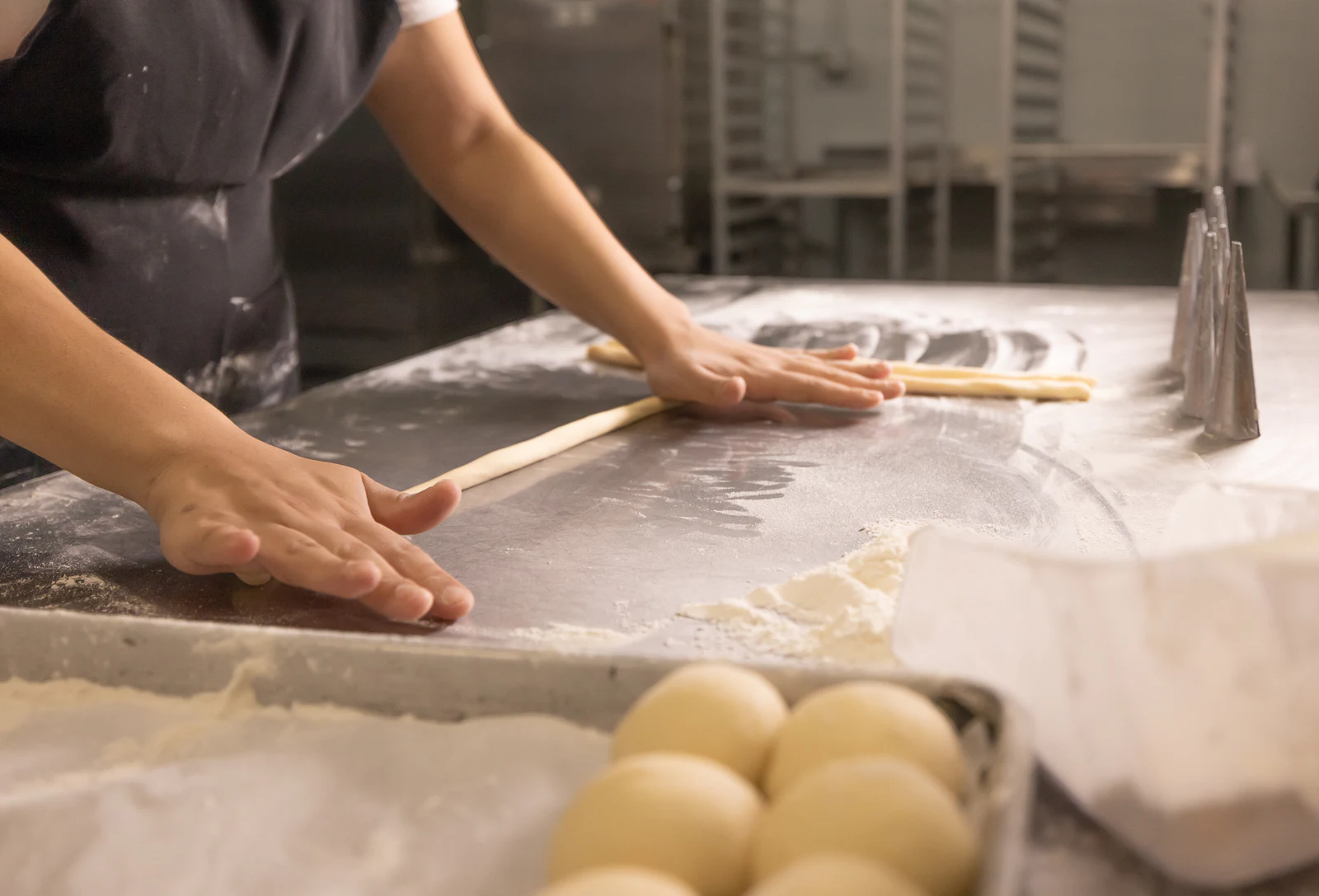 Hands shaping pastry dough on a floured worktable